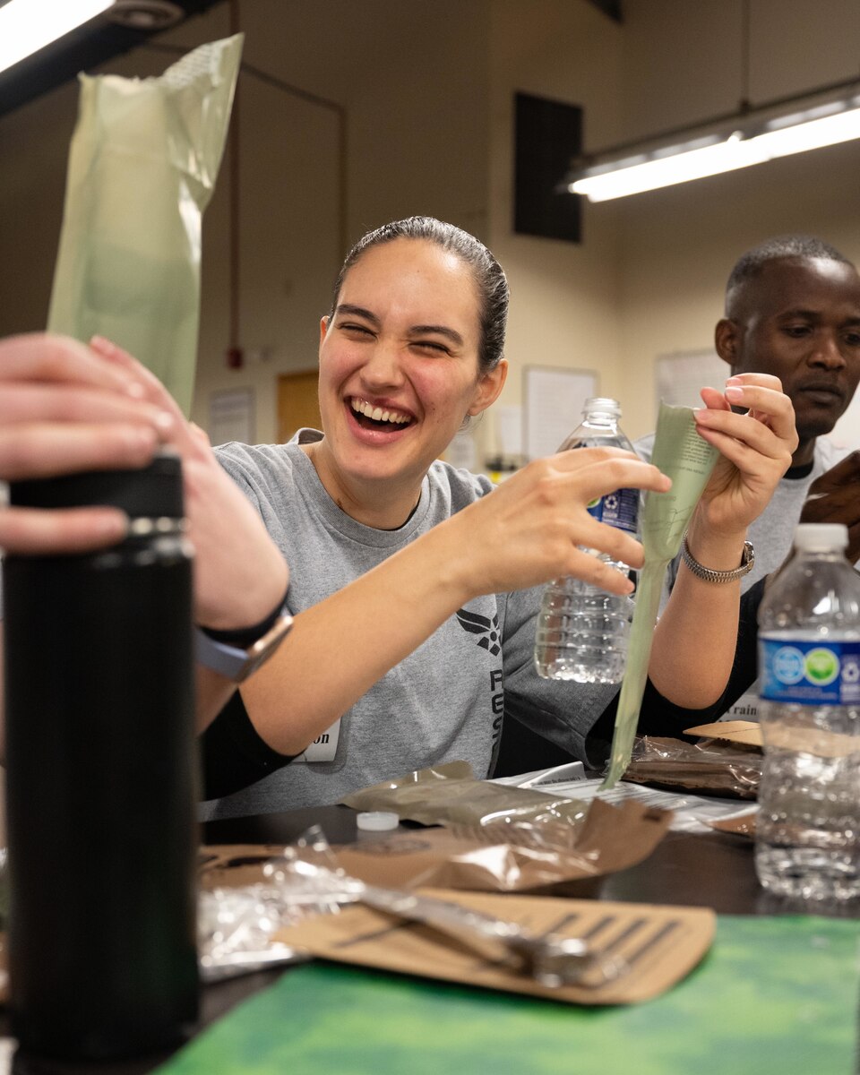 Trainee Rachel Peterson, 934th Airlift Wing Development and Training Flight trainee, prepares to pour water into a portable flameless ration heater in her meal ready-to-eat at the D&TF building at the Minneapolis-St. Paul Air Reserve Station, Minnesota, March 5, 2023. Peterson said she enjoyed the experience of heating, unpacking, and eating an MRE for the first time. (U.S. Air Force photo by Senior Airman Victoriya Tarakanova)