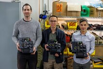 Engineers in Naval Surface Warfare Center, Carderock Division’s Expeditionary and Development Power and Energy Branch from left: Matthew Huffman, technical area lead, Kevin Lin, electrical engineer and James Mulford, mechanical engineer, display their invention, the Lithium 6T Top Cap, in West Bethesda, Md., on March 8. The engineers are shown with three of their four prototypes, which is a modular, field-reconfigurable direct current power distribution device that can be installed and mounted on top of a Li6T battery. (U.S. Navy photo by Aaron Thomas)