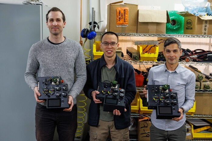 Engineers in Naval Surface Warfare Center, Carderock Division’s Expeditionary and Development Power and Energy Branch from left: Matthew Huffman, technical area lead, Kevin Lin, electrical engineer and James Mulford, mechanical engineer, display their invention, the Lithium 6T Top Cap, in West Bethesda, Md., on March 8. The engineers are shown with three of their four prototypes, which is a modular, field-reconfigurable direct current power distribution device that can be installed and mounted on top of a Li6T battery. (U.S. Navy photo by Aaron Thomas)