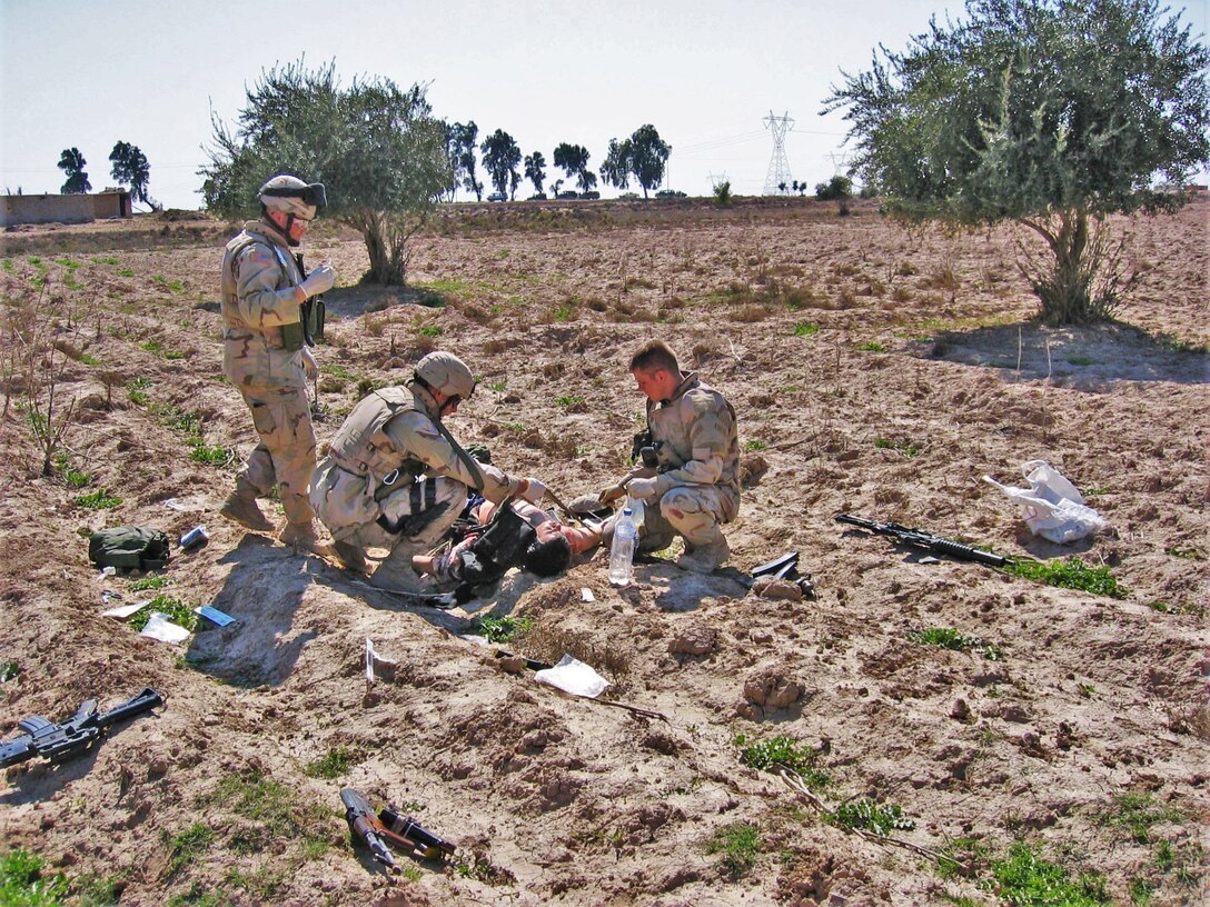 (Left to right) Spc. Jeremy Eades, Sgt. William Baum and Spc. Casey Cooper, all military policemen, 4th Platoon, 617th Military Police Company, 503rd MP Battalion, 18th MP Brigade, provide medical assistance to a wounded insurgent after a group of insurgents attacked a supply convoy March 20, 2005, about 18 miles southeast of Baghdad. The 617th Soldiers successfully defended the convoy and defeated the insurgents, killing 27, wounding six and capturing one. (U.S. Army photo by Sgt. 1st Class Marshall P. Ware)