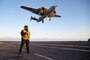 Aviation Boatswain's Mate (Equipment) 1st Class Aaron Wilson, from Atlanta, assigned to USS Gerald R. Ford’s (CVN 78) air department, stands watch as the arresting gear officer as an E2-D Hawkeye, attached to the "Bear Aces" of Airborne Command and Control Squadron (VAW) 124, flies over the flight deck, April 19, 2022. Ford is underway in the Atlantic Ocean conducting carrier qualifications and strike group integration as part of the ship’s tailored basic phase prior to operational deployment. (U.S. Navy photo by Mass Communication Specialist 2nd Class Zachary Melvin)