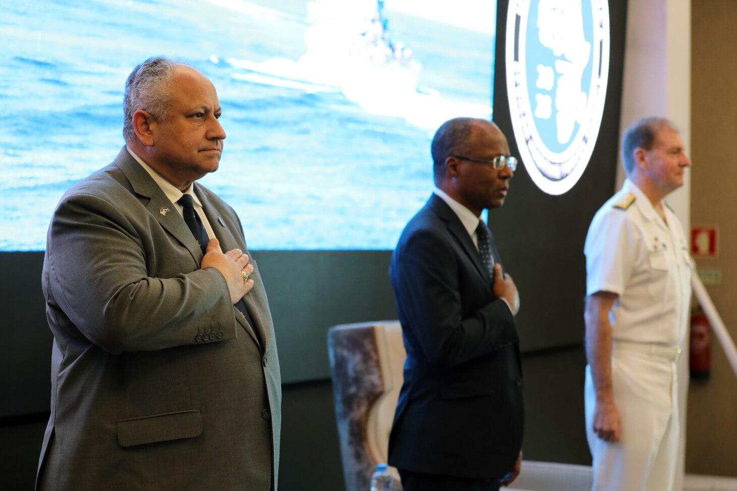 (March 20, 2023) Secretary of the Navy Carlos Del Toro (left), Cabo Verde Prime Minister Ulisses Correa e Silva (center), and U.S. Navy Adm. Stuart B. Munsch, Commander of U.S. Naval Forces Europe-Africa (NAVEUR-NAVAF), stand for the national anthem of the Republic of Cabo Verde during the opening ceremony of the African Maritime Forces Summit (AMFS), Mar. 20 2023. Hosted by NAVEUR-NAVAF, the AMFS is a strategic-level forum that brings African maritime and naval infantry leaders together with their international partners to address transnational maritime security challenges within African waters including the Atlantic Ocean, Indian Ocean, and Mediterranean Sea.