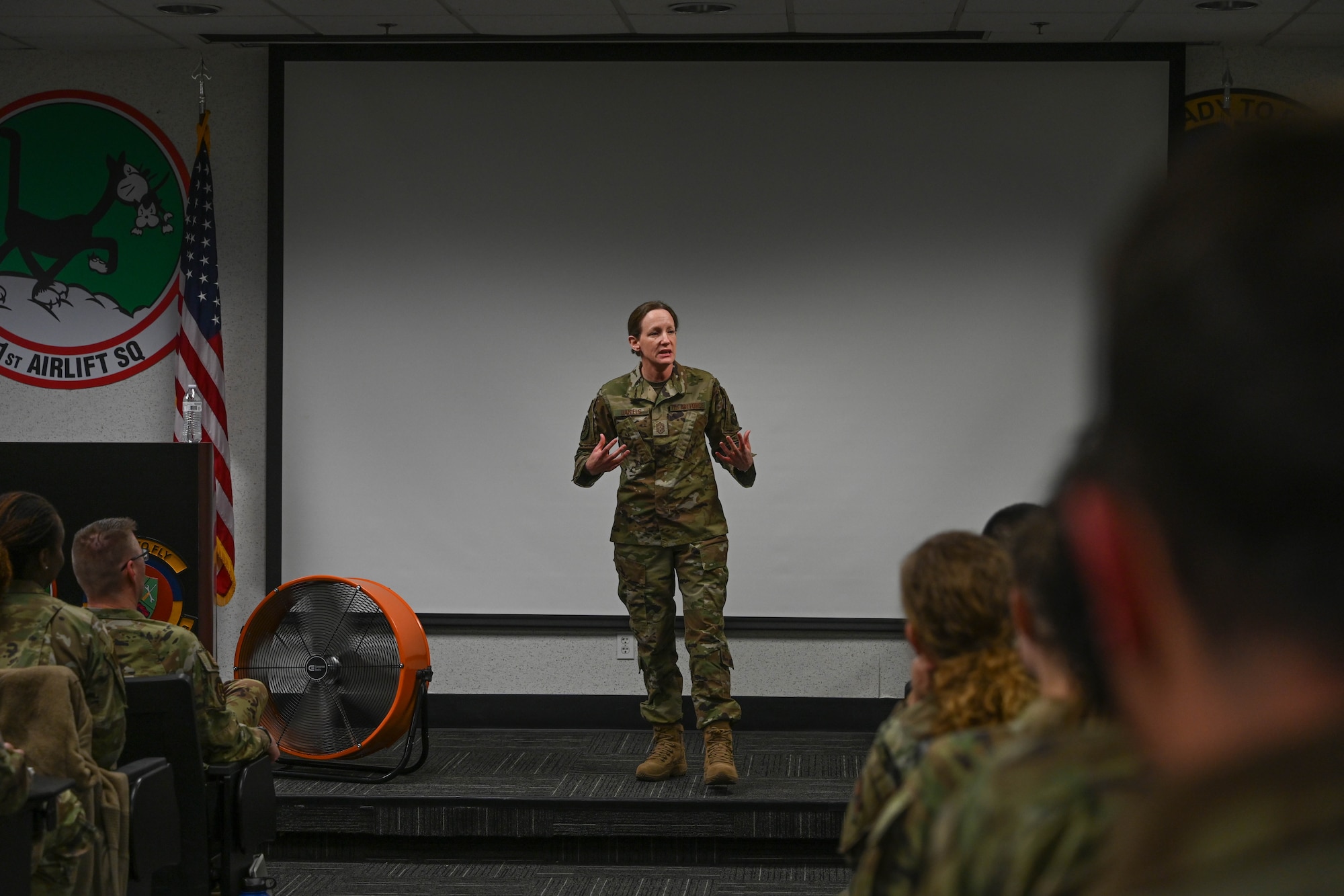 A woman in uniform stands on a stage.