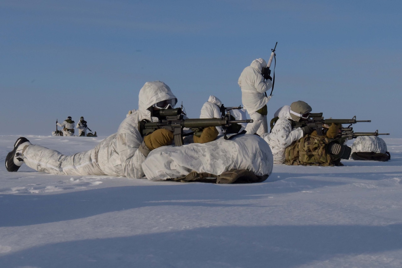 Soldiers lie on the ground holding weapons.