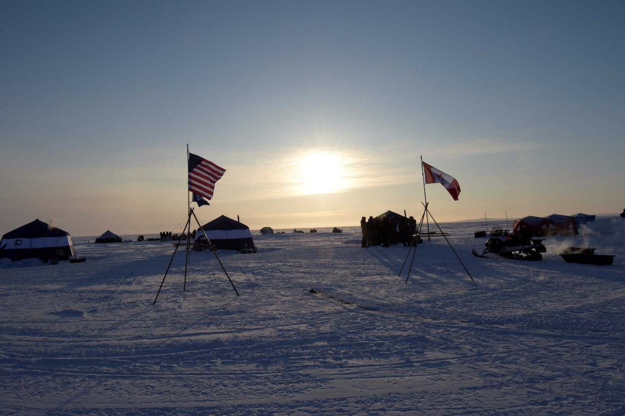 A U.S. and Canadian flag displayed in the snow.