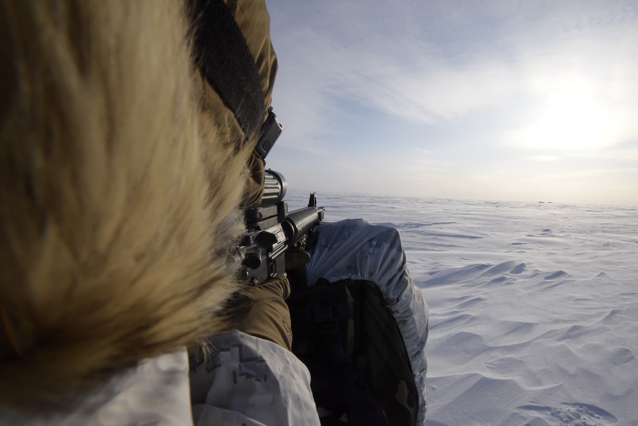 A soldier looks through the viewfinder of a weapon.