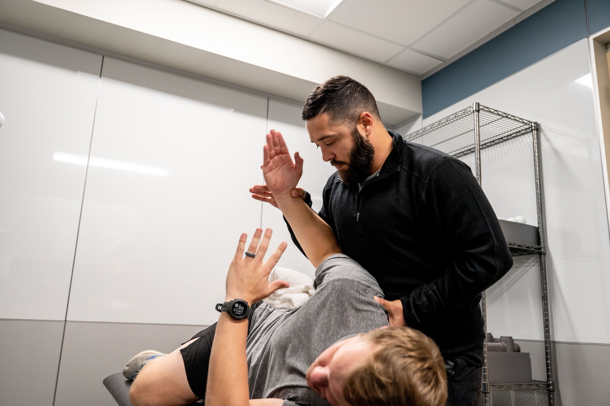athletic trainer stretches patient's arm in a clinic