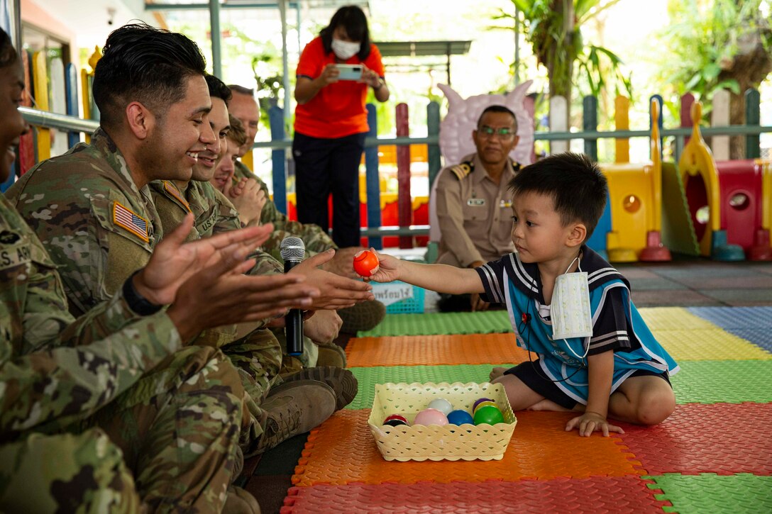 U.S. Army soldiers play a game with a child at a community outreach event during Exercise Cobra Gold in Rayong Province, Kingdom of Thailand, March 9, 2023.