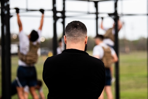 Athletic Trainer watches as candidates complete a round of pull-ups outdoors