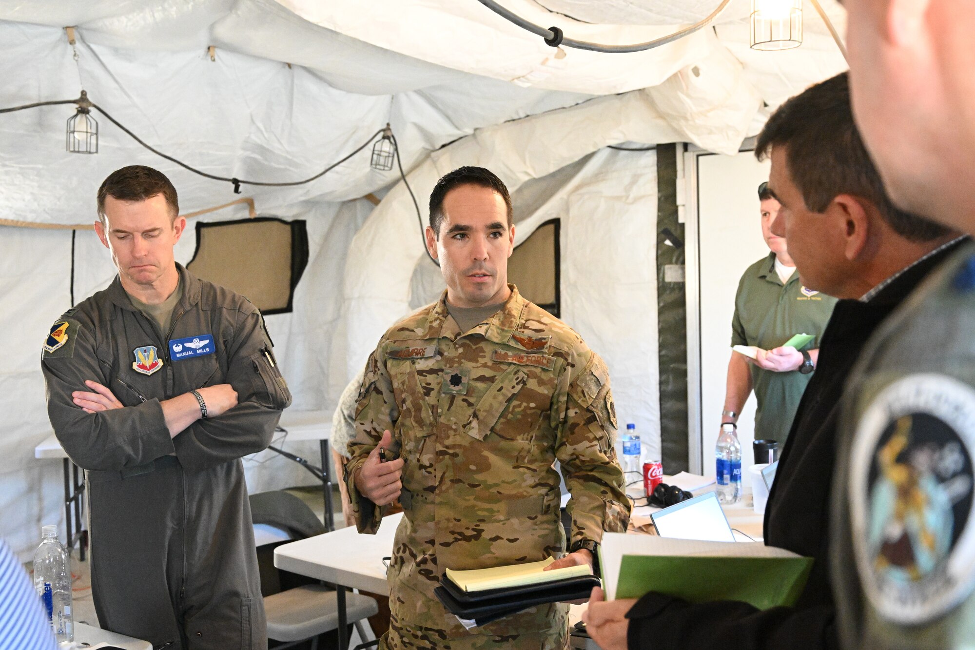 photo of four uniformed U.S. Air Force military personnel standing in a white tent talking