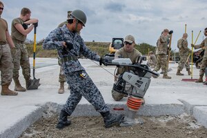Airmen and allies use a dirt compactor.