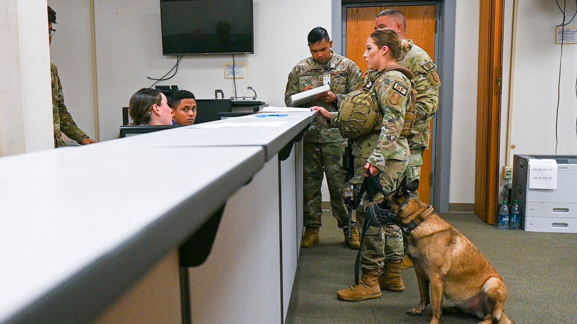 Senior Airman Christal Schaff, 647th Security Forces Squadron military working dog  handler, and military working dog Ula, process through the pre-deployment function line at Joint Base Pearl Harbor-Hickam, Hawaii, during the Joint Base Readiness Exercise, Feb. 28, 2022. The pre-deployment function line ensures airmen are equipped with proper documentation and essentials prior to deployment. (U.S. Air Force photo by Senior Airman Makensie Cooper)