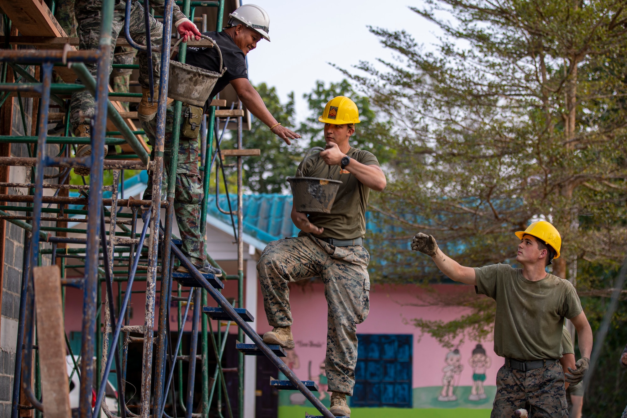 Royal Thai Marines and U.S. Marines with Marine Wing Support Squadron (MWSS) 171, form a human conveyor belt to transport buckets of mortar for wall construction during Exercise Cobra Gold 23 (CG23) at Chanthaburi, Kingdom of Thailand, Feb. 20, 2023.