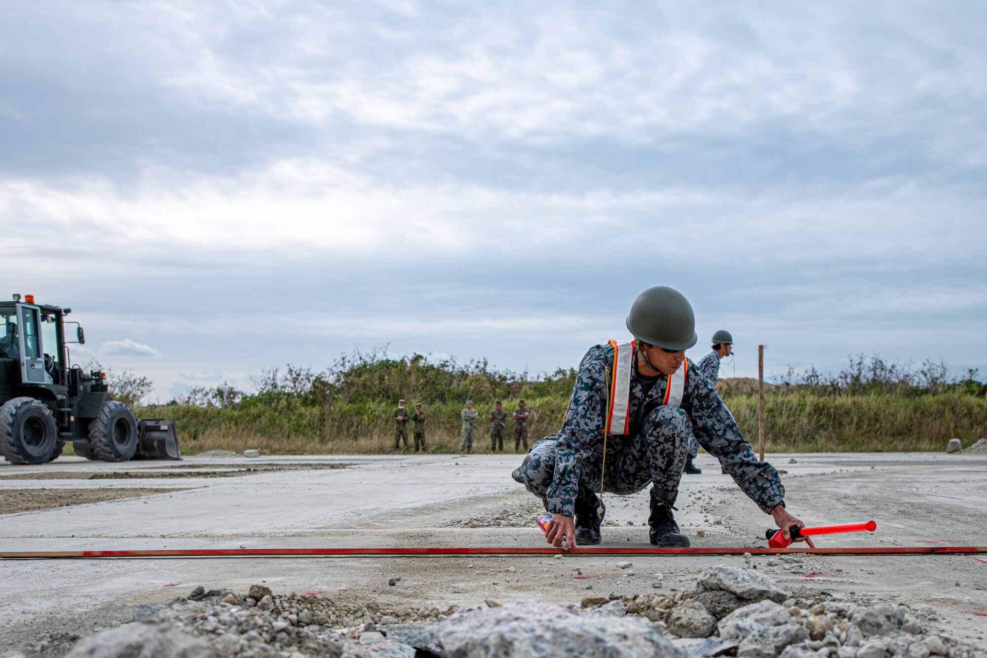 A JASDF member measures a simulated damage site.