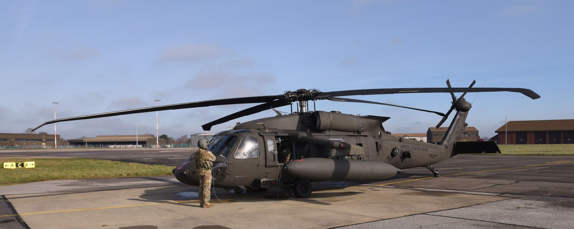 A U.S. Army UH-60M Black Hawk from the 1st Battalion, 214th Aviation Regiment (General Support Aviation Battalion), Wiesbaden, Germany, sits on the flightline as its maintainers and aircrew prep it for takeoff at Royal Air Force Mildenhall, England, March 15, 2023. The helicopters stopped off for refueling and rest before heading to RAF Leeming, Scotland. (U.S. Air Force photo by Karen Abeyasekere)