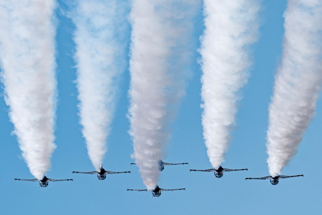 Six aircraft leave trails of smoke in the sky.