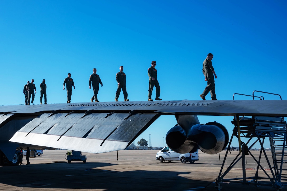 Airmen walk along a wing of a plane.