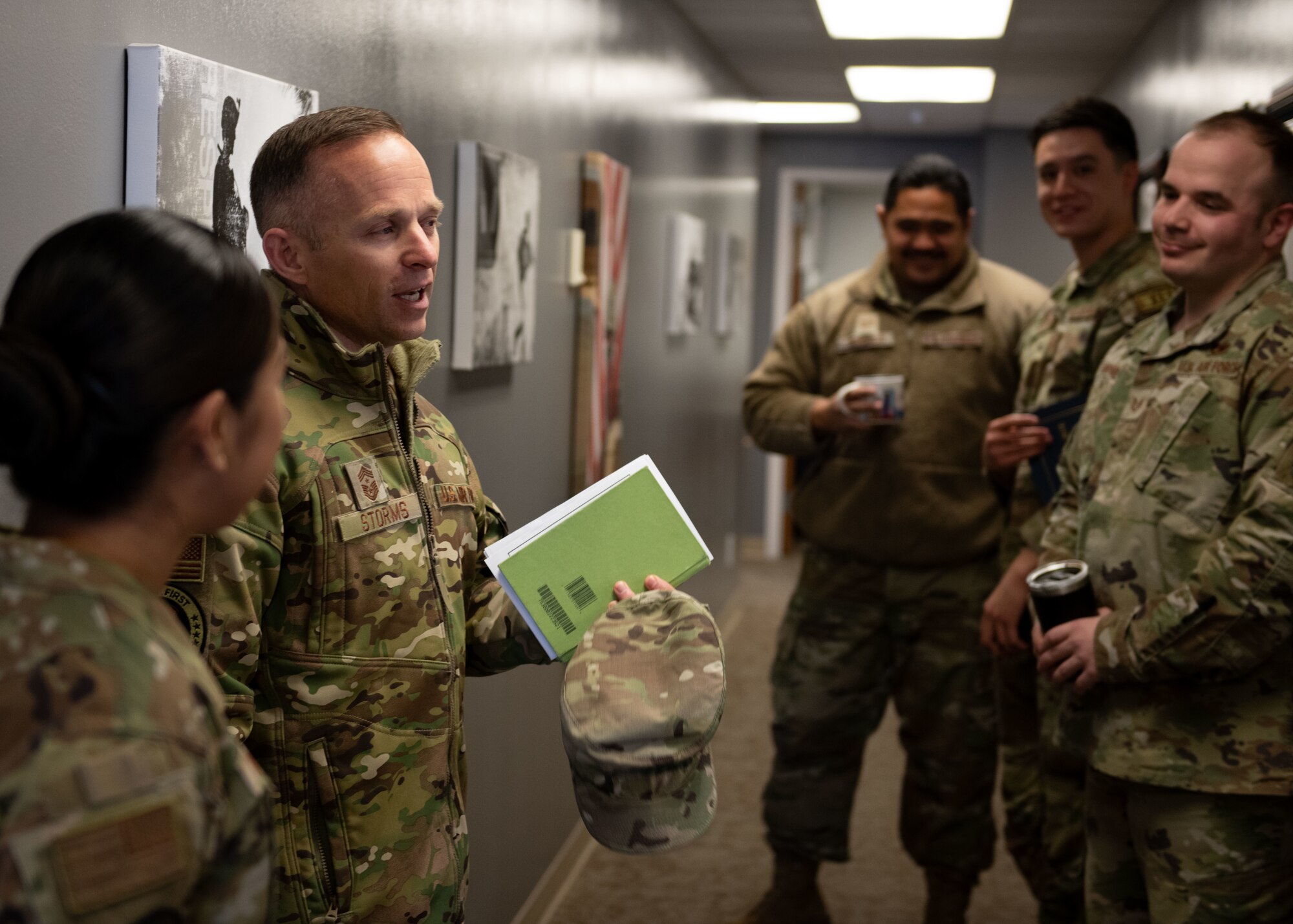 Chief speaks with airmen in a hallway.