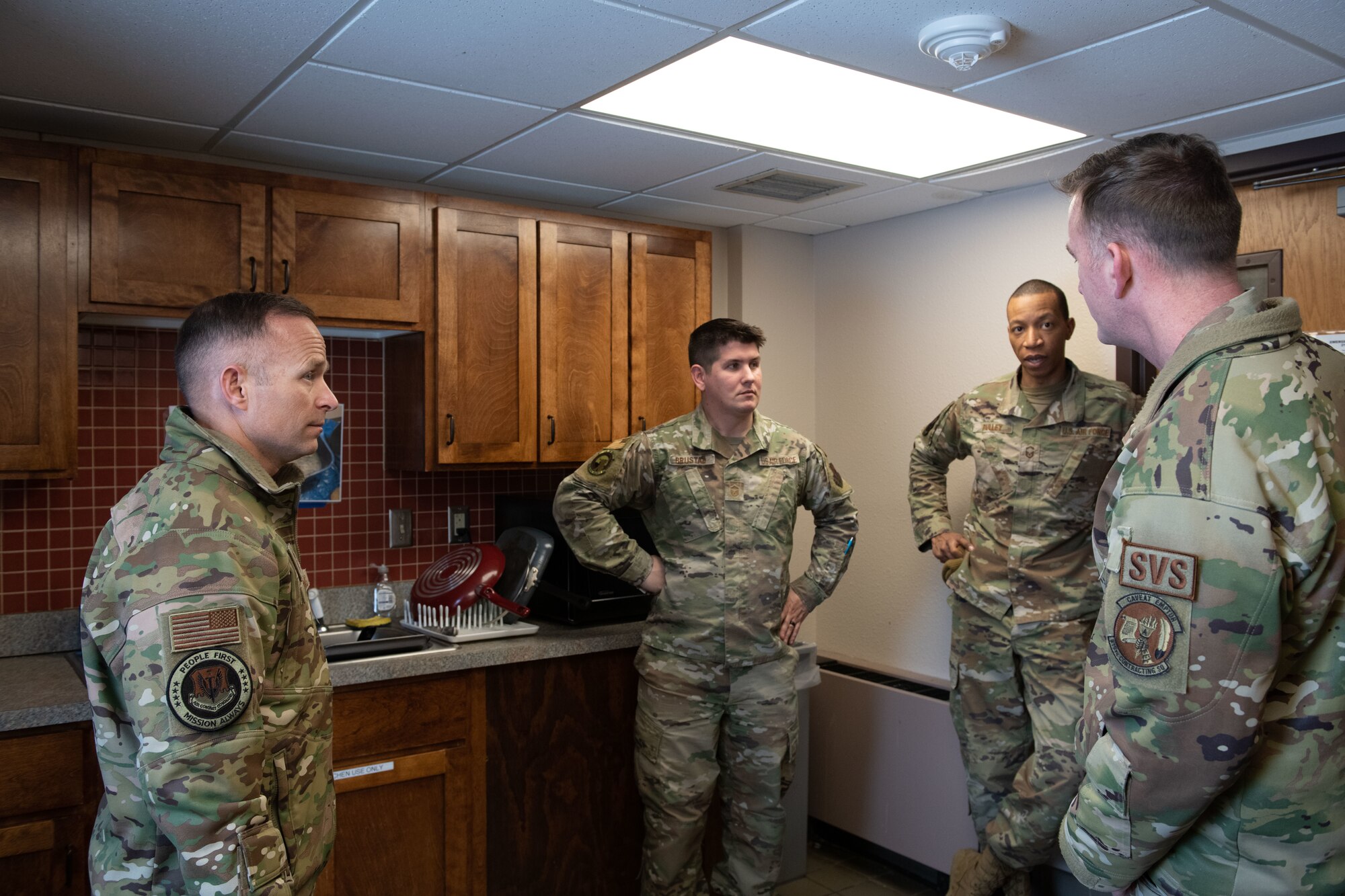 Airmen conversate in dorm kitchen.