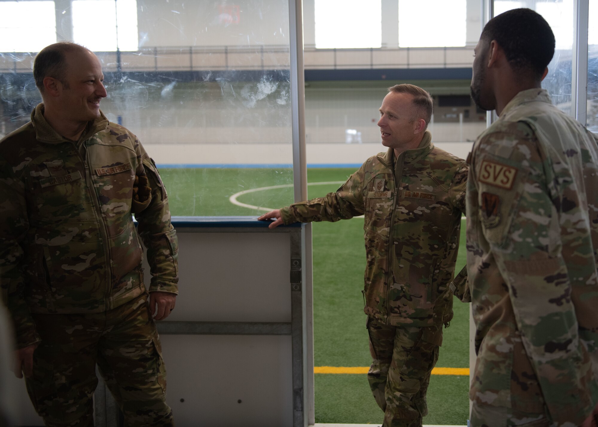 Airmen conversate in an indoor court.