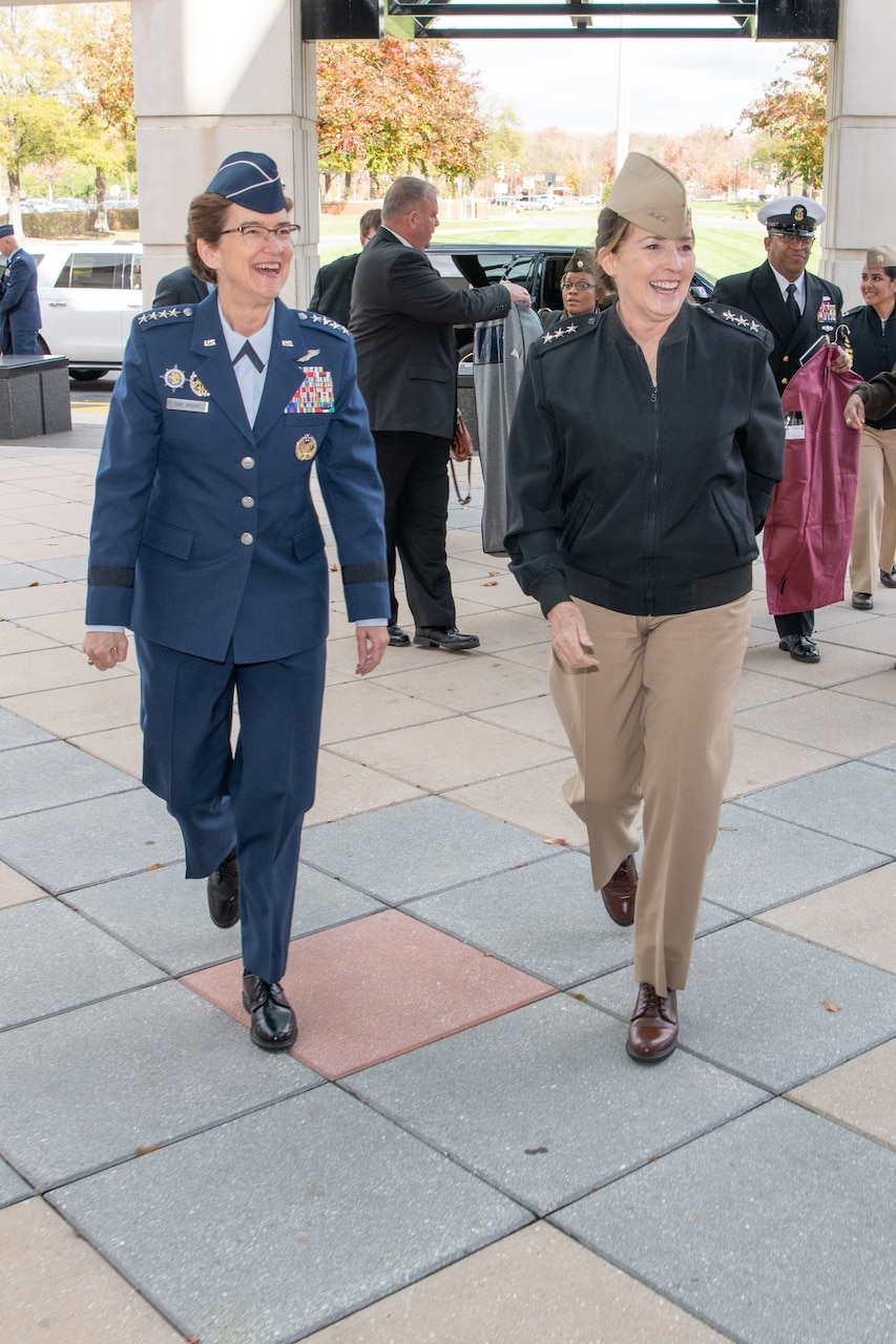 Two uniformed service members walk side by side smiling.