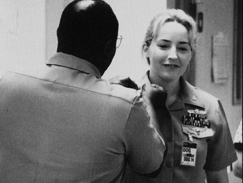A uniformed service member smiles while getting new rank insignia pinned on her uniform.
