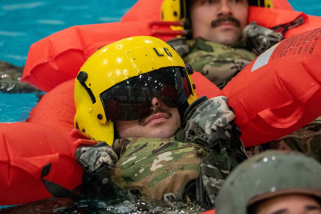 Uniformed soldiers wear floatation vests in a pool.