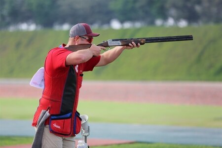 Man with shotgun shoots a clay target.