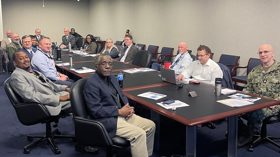 A group of people sit around a table during a meeting.