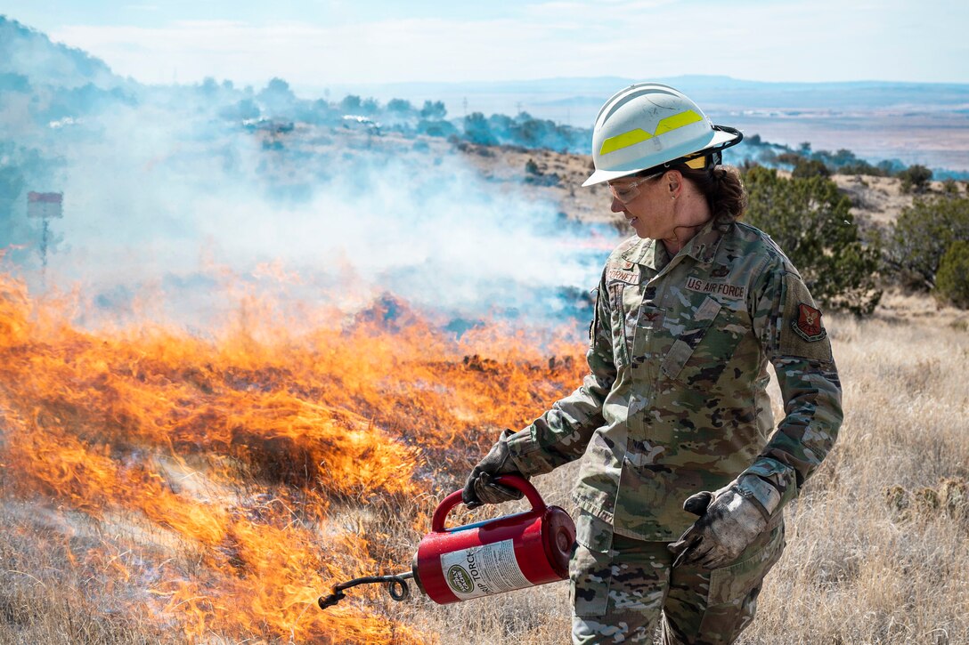 An airman assists with a fire in a field.