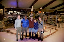 plain clothes military members posing for photo in front of aircraft