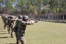 Multiple men in U.S. Army uniforms on outdoor pistol range.