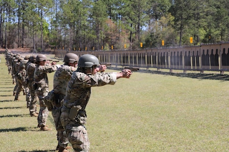 Multiple men in U.S. Army uniforms on outdoor pistol range.