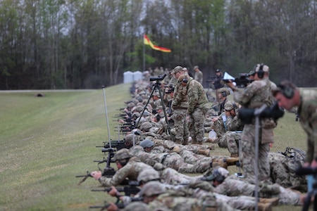 Multiple men in U.S. Army uniforms on outdoor rifle range.