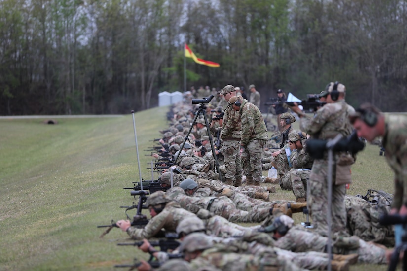 Multiple men in U.S. Army uniforms on outdoor rifle range.