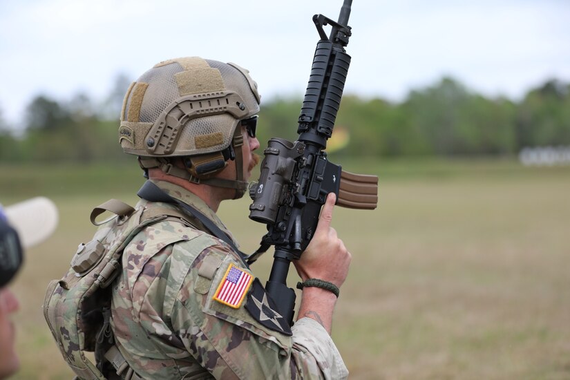 Man in U.S. Army uniform with rifle on outdoor rifle range.