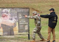 Man in U.S. Army uniform on firing pistol on outdoor range.