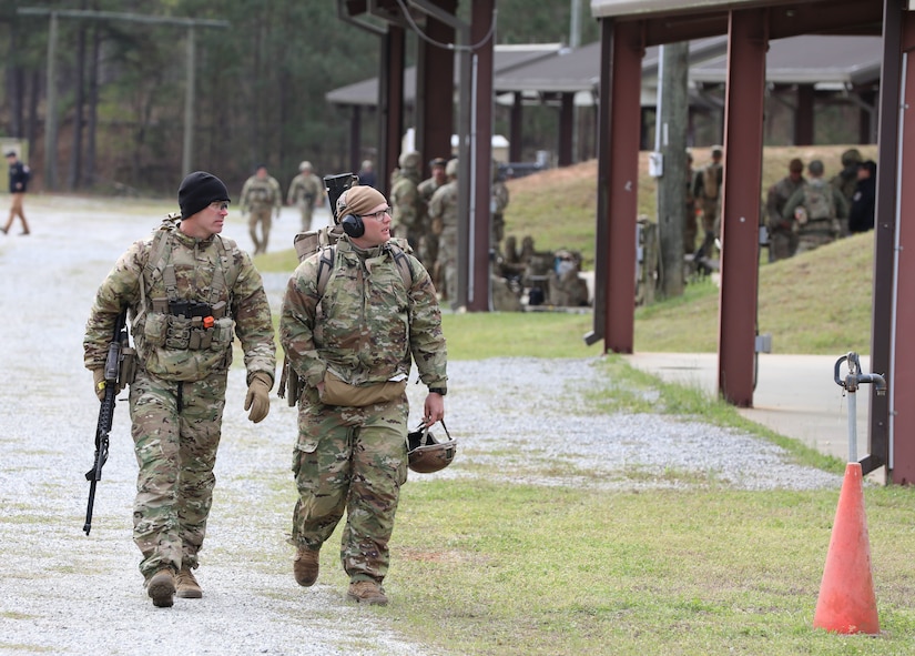 2 men in U.S. Army uniforms walk to the next competition stage outdoors.