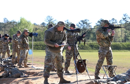 Multiple men in U.S. Army uniforms on outdoor rifle range.