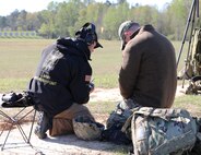 2 men check scorecard at outdoor shooting range.