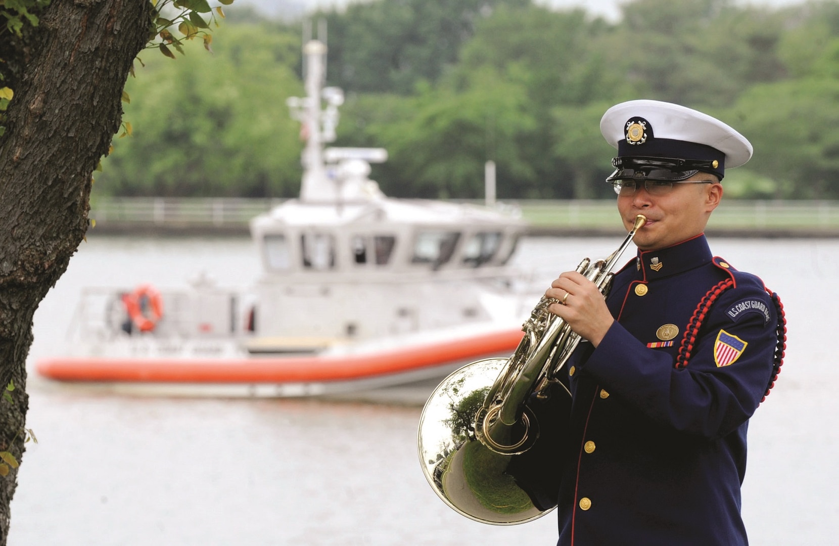 A U.S. Coast Guard Band member warms up as a boat patrols the Potomac near Ft. McNair during the U.S. Coast Guard Change of Command Ceremony, May 25, 2010.  Adm. Thad W. Allen was relieved by Adm. Robert J. Papp, Jr., as commandant of the U.S. Coast Guard in a ceremony presided over by Department of Homeland Security Secretary Janet Napolitano.  DOD photo by Cherie Cullen (released)