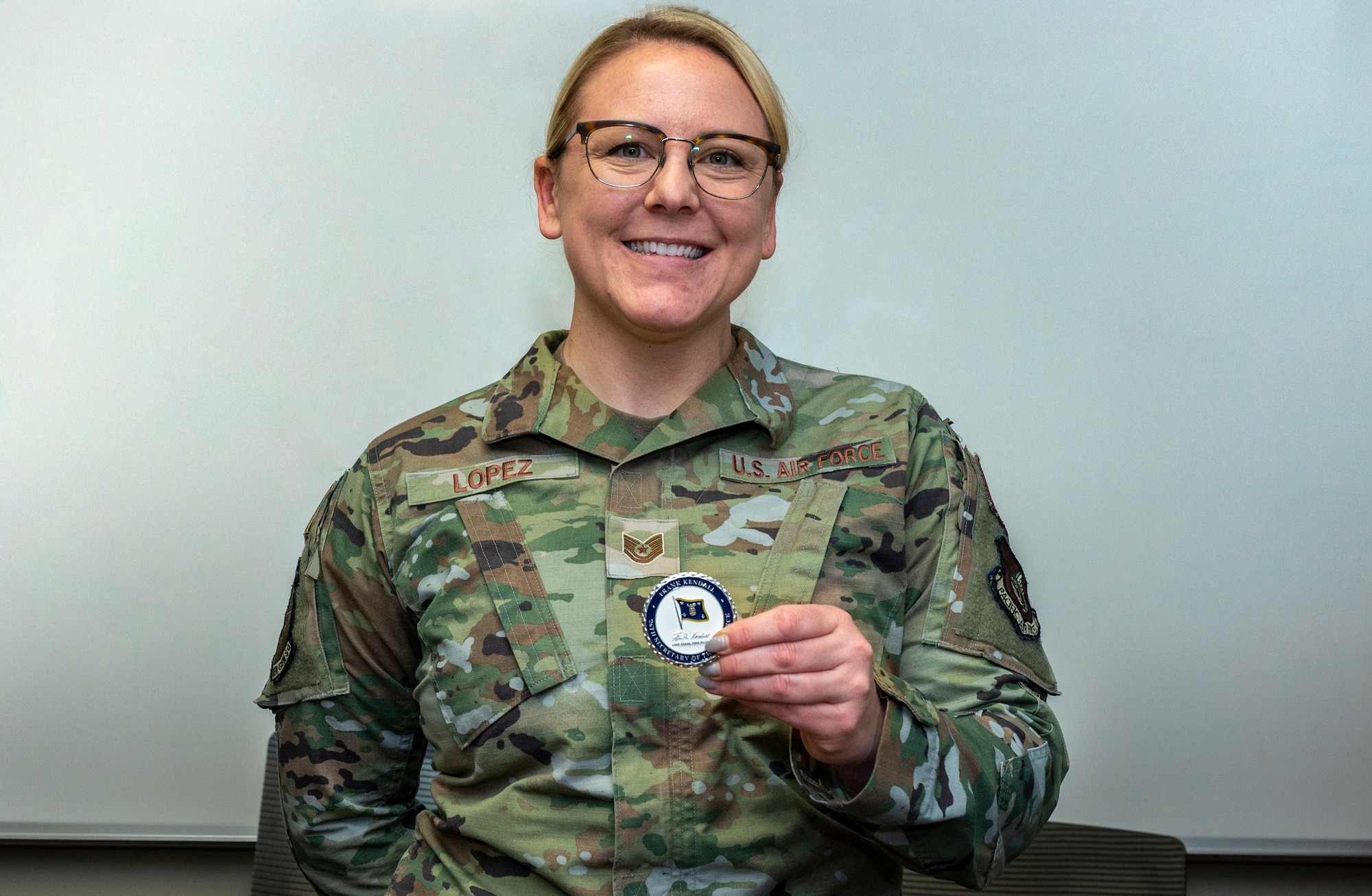 U.S. Air Force Tech. Sgt. Brooke Lopez, 25th Fighter Generation Squadron expeditor, displays her coin presented by Secretary of the Air Force Frank Kendall at Osan Air Base, Republic of Korea, March 20, 2023.