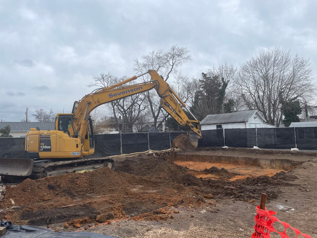 An excavator removes soil from a fenced in area