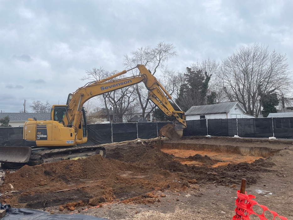 An excavator removes soil from a fenced in area