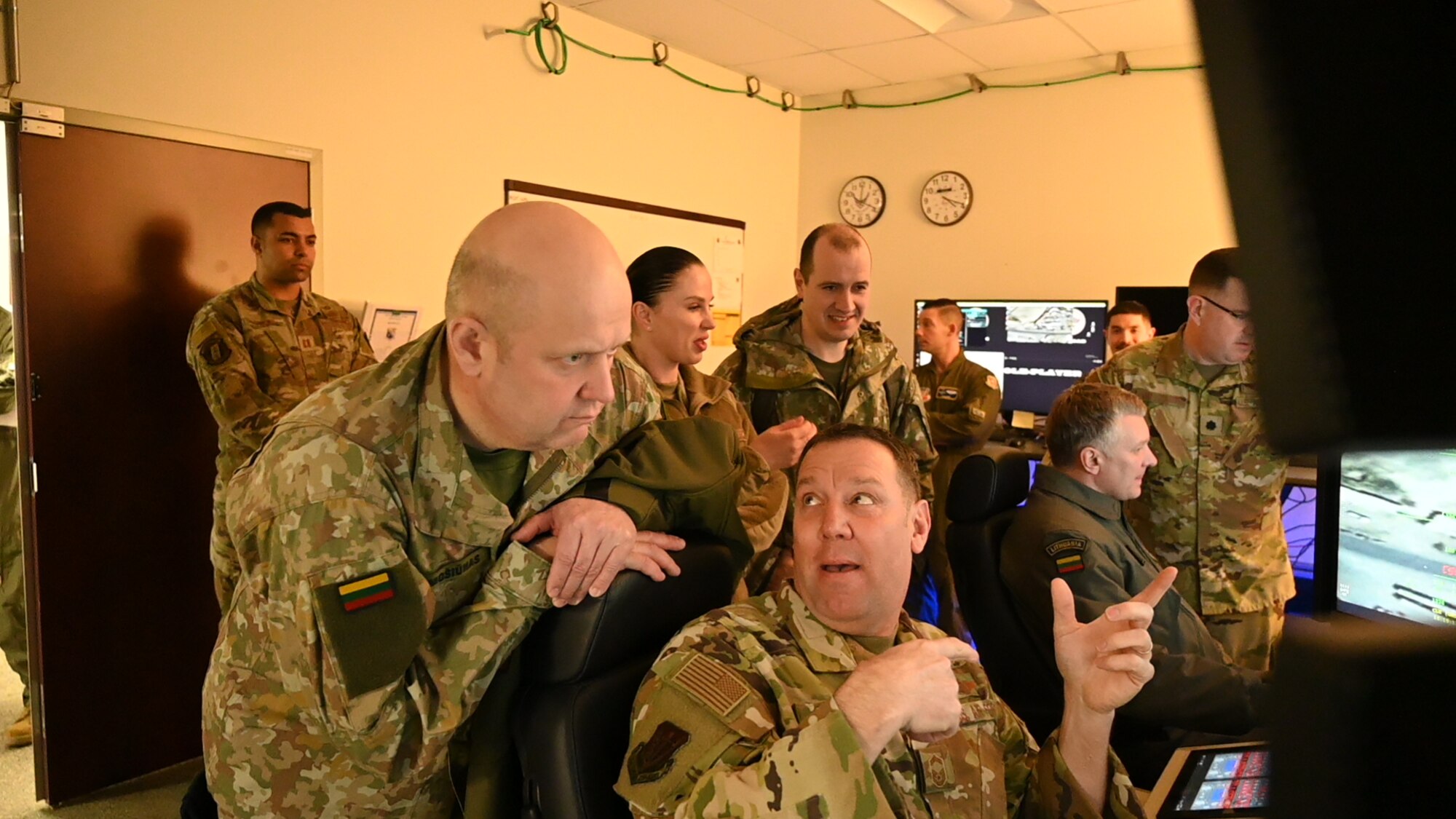 Military personnel surround a flight simulator.