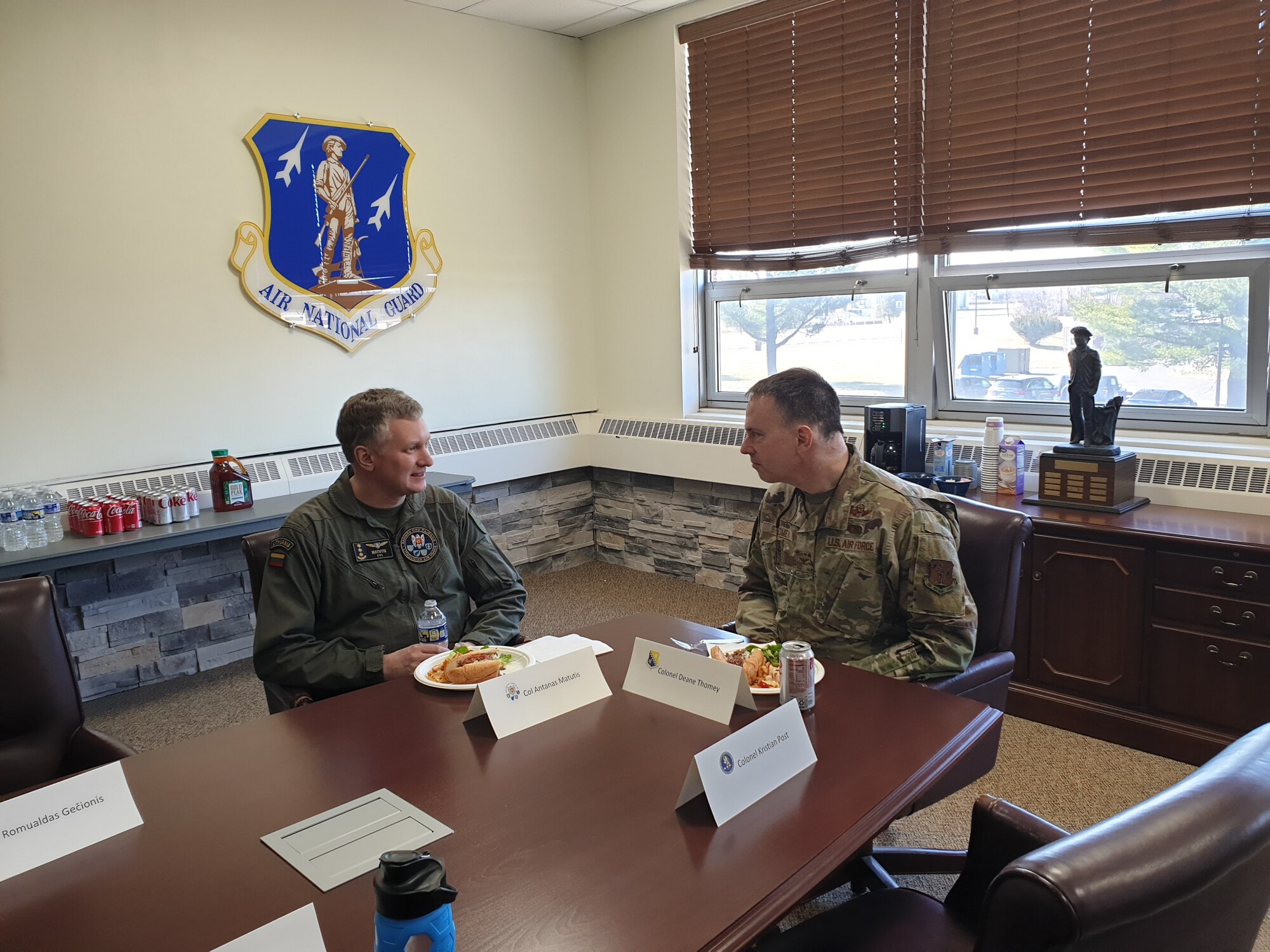 Two men in military uniforms sit at a table.
