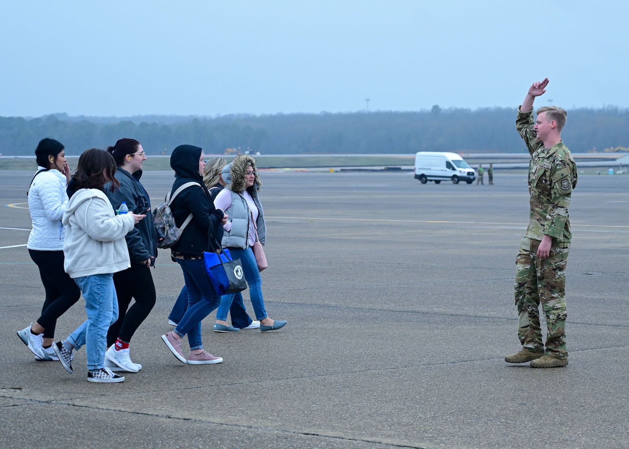 A loadmaster directs families on airfield