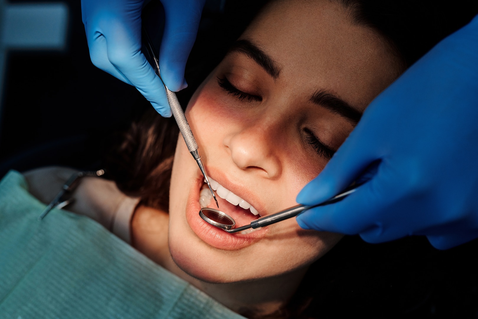 A dentist probes a woman's teeth with dental tools