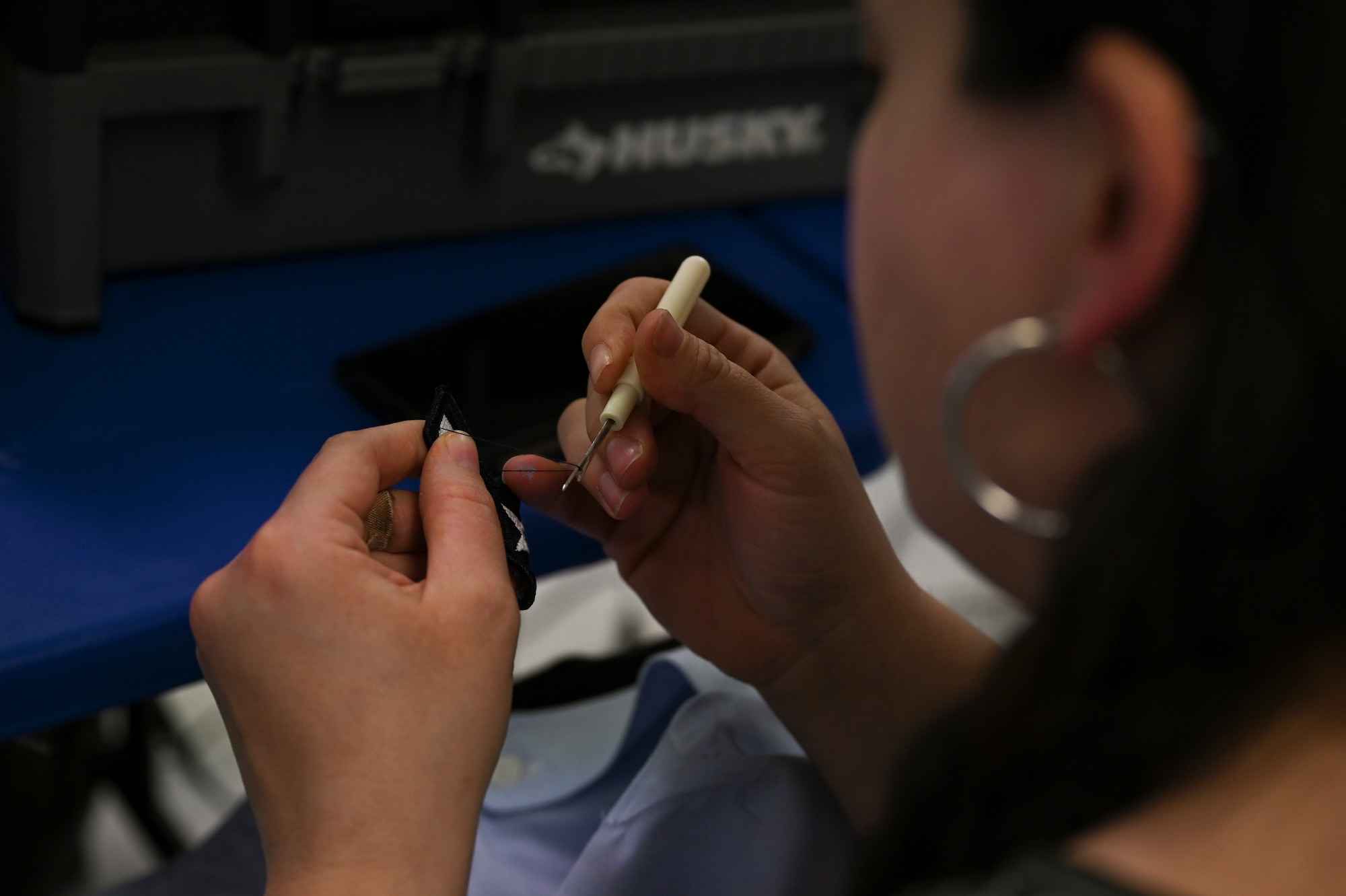 A woman sews a patch.