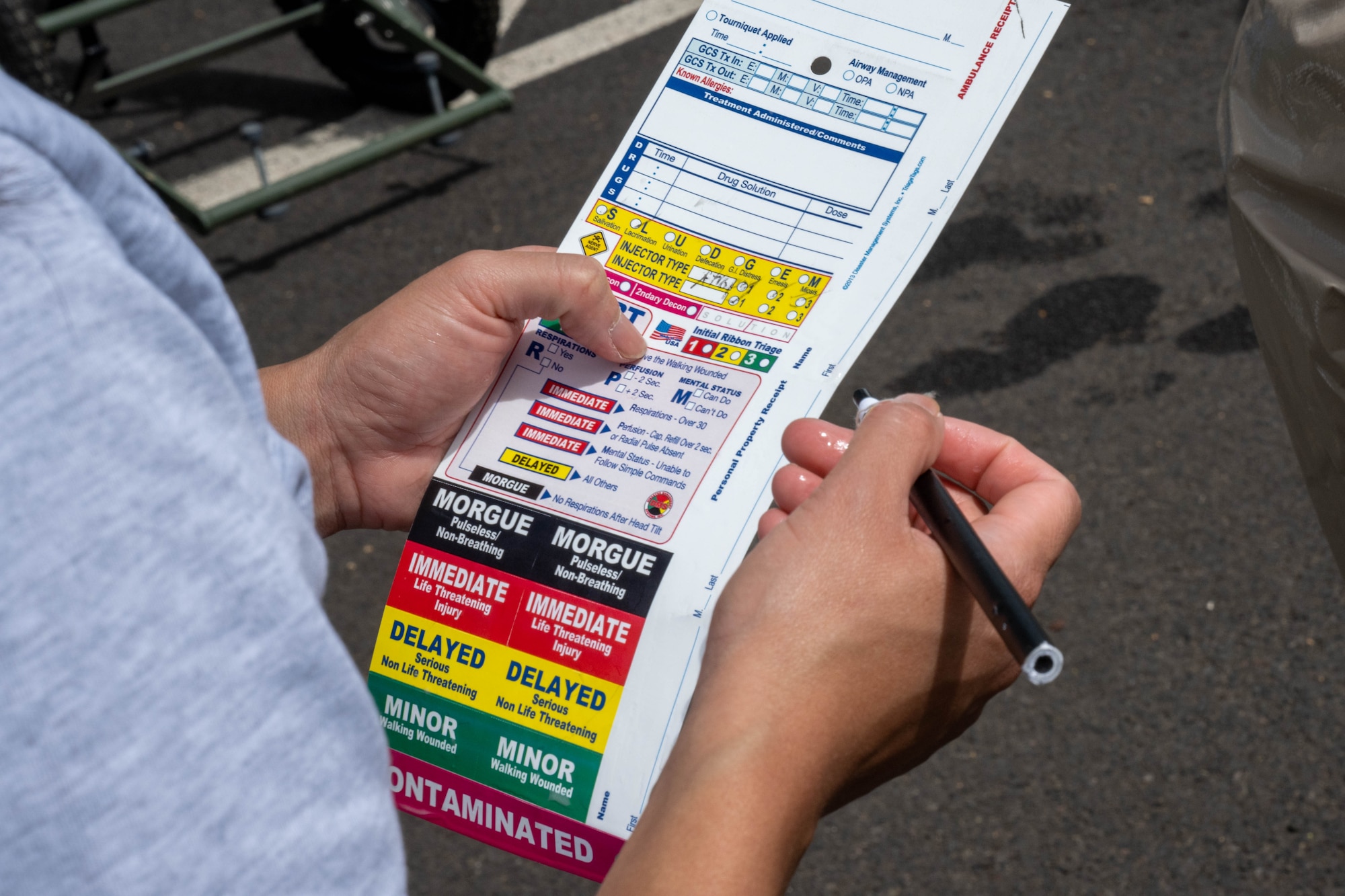 An airmen assigned to the 15th Medical Group decontamination team fills out a field triage card during a contamination drill at Joint Base Pearl Harbor-Hickam, Hawaii, March 2, 2023. This training teaches and refreshes 15th MDG medical personnel DECON procedures to help protect the military treatment facility and personnel from further contamination. (U.S. Air Force photo by Senior Airman Makensie Cooper)
